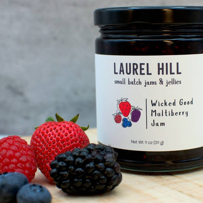 Jar of Laurel Hill Wicked Good Multiberry Jam with berries on a wooden surface