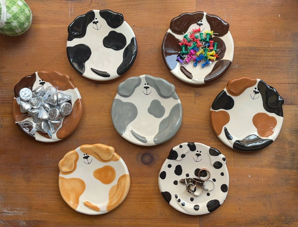 Set of ceramic dog plates with different designs on a wooden surface