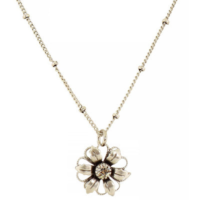 A silver-tone flower pendant necklace on a delicate chain, featuring a central clear gemstone surrounded by textured petals, set against a plain white background.