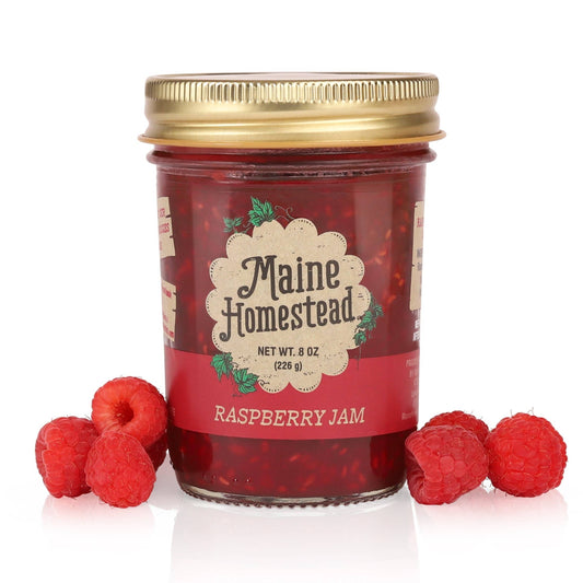 Jar of Maine Homestead Raspberry Jam with raspberries on a white background