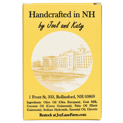 A yellow rectangular box with black text reading 'Handcrafted in NH by Joel and Katy' and a sepia illustration of a building in a circular inset. The box also includes an address and ingredient list, plus 'Restock at JoyLaneFarm.