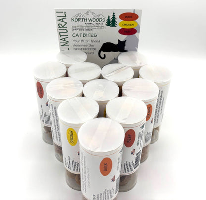 A group of North Woods Animal Treats cat bite containers arranged in a circle, with the product box standing behind them on a white background.