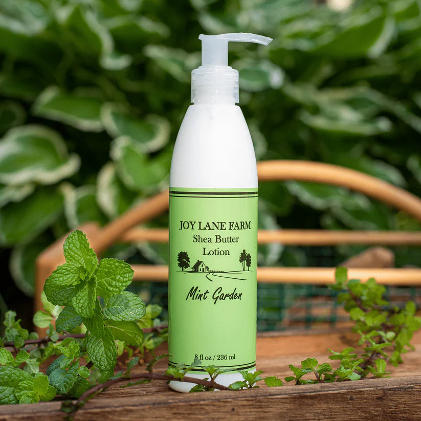 Shea butter lotion bottle with green label on a wooden surface with plants