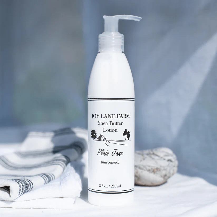 White lotion bottle labeled 'Joy Lane Farm Shea Butter Lotion' on a neutral background