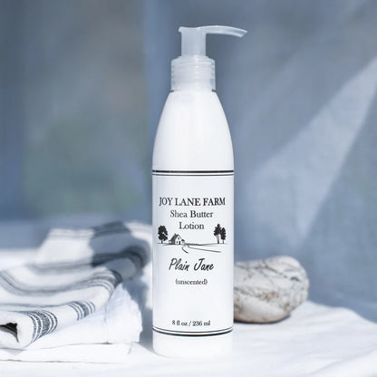 White lotion bottle labeled 'Joy Lane Farm Shea Butter Lotion' on a neutral background