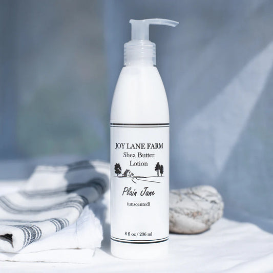 White lotion bottle labeled 'Joy Lane Farm Shea Butter Lotion' on a neutral background