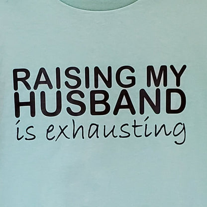 Light blue t-shirt with text 'RAISING MY HUSBAND is exhausting' on a light blue background