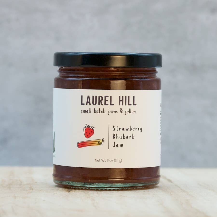 Jar of Laurel Hill Strawberry Rhubarb Jam on a wooden surface with a gray background