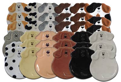 A set of ceramic dog-shaped plates arranged in rows, showing multiple color options including black and white, tan and brown, cream and beige, and solid black and white.
