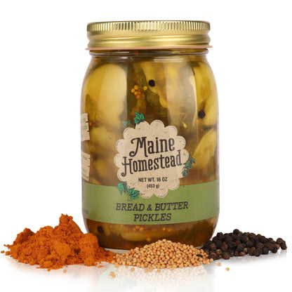 Jar of Maine Homestead bread and butter pickles with spices on a white background
