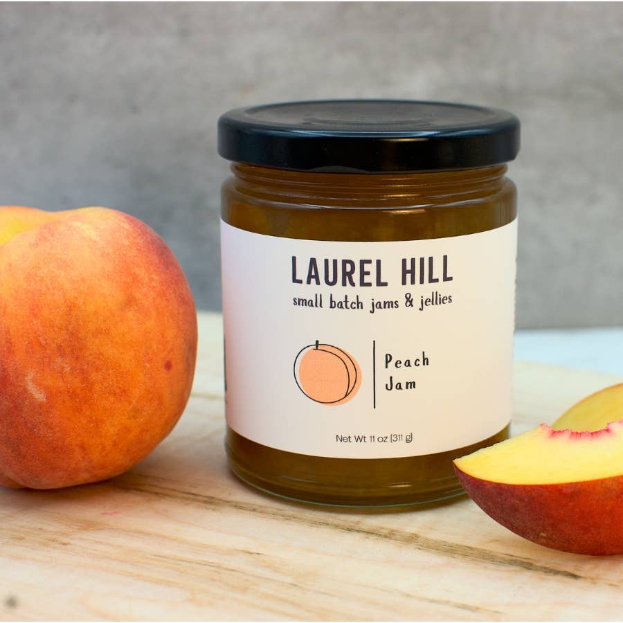 Jar of Laurel Hill Peach Jam with a peach on a wooden surface