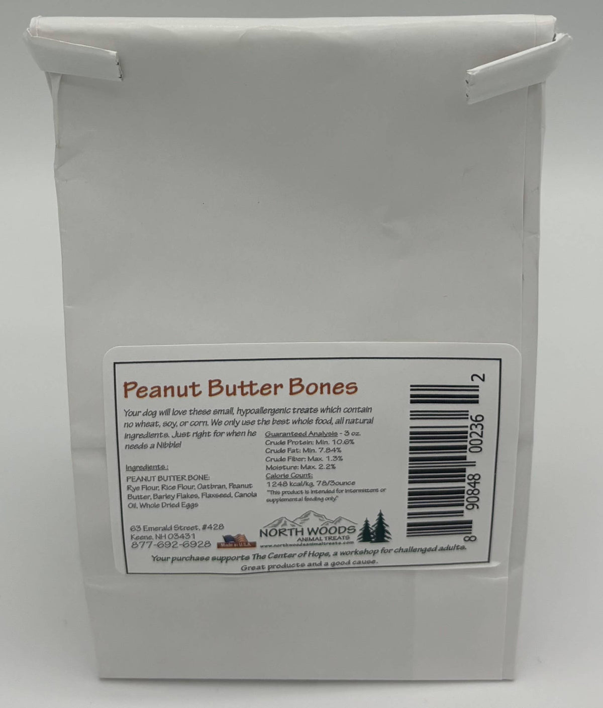A white paper bag of North Woods Apothecary 'Peanut Butter Bones' on a light gray background.