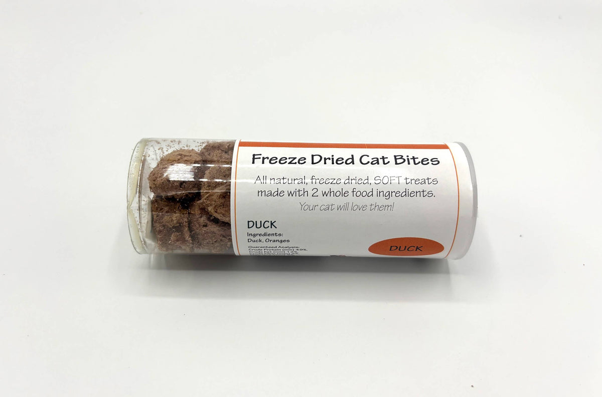 A clear plastic tube of Duck Freeze Dried Cat Bites, showing the brown freeze-dried treats inside, with a white and orange label, on a plain white background.