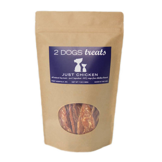 A 7 oz stand-up pouch of '2 DOGS treats' Just Chicken dog treats, made from brown kraft paper with a dark blue label and a clear window showing the treats inside.