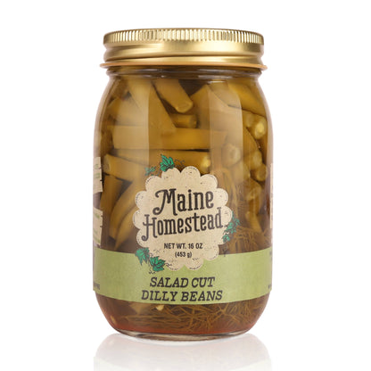 A glass jar of Maine Homestead Salad Cut Dilly Beans with a gold metal lid and a light green label, set against a plain white background.