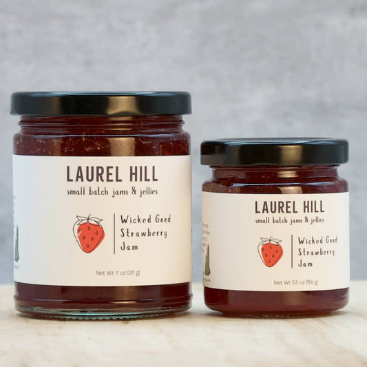 Two jars of Laurel Hill Wicked Good Strawberry Jam on a neutral background