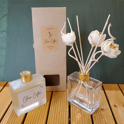 Decorative flower vase with a bottle of perfume and packaging on a wooden surface.