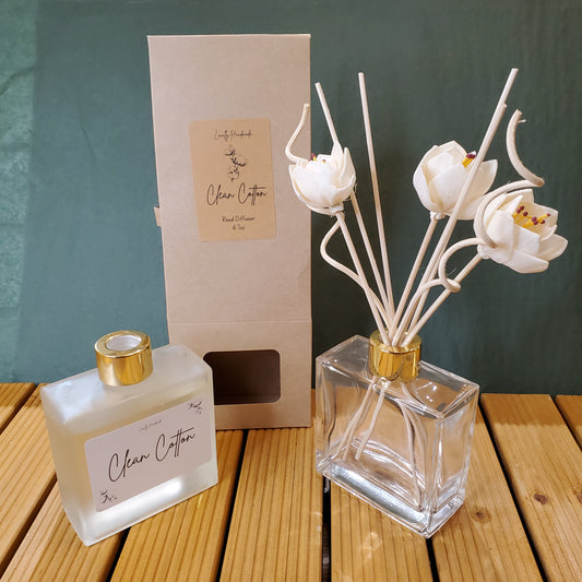 Decorative flower vase with a bottle of perfume and packaging on a wooden surface.