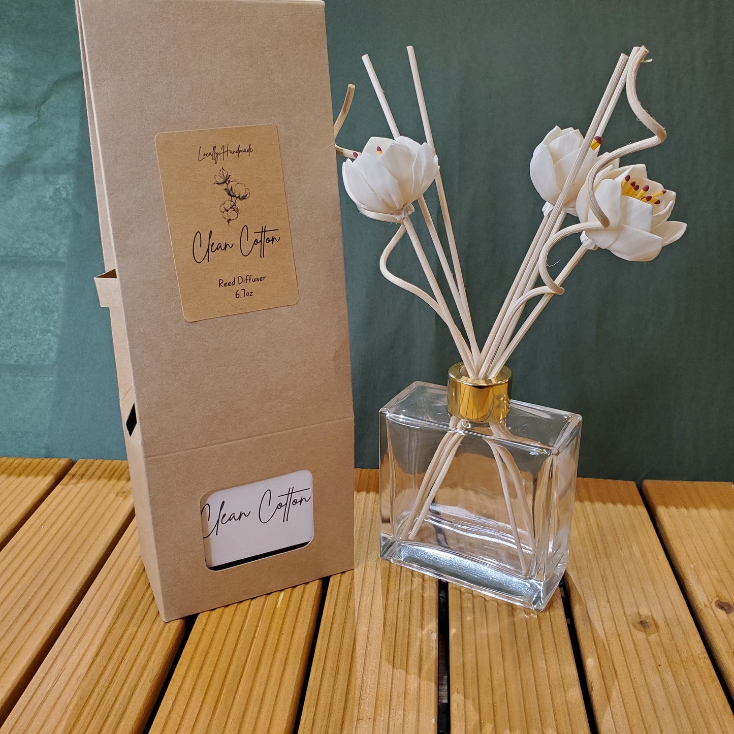 Clear glass diffuser with white floral reeds on a wooden surface