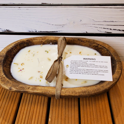 Candle in a wooden dish with a warning label on a wooden surface