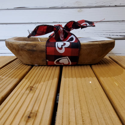 Wooden bowl with a red and black checkered ribbon on a wooden surface