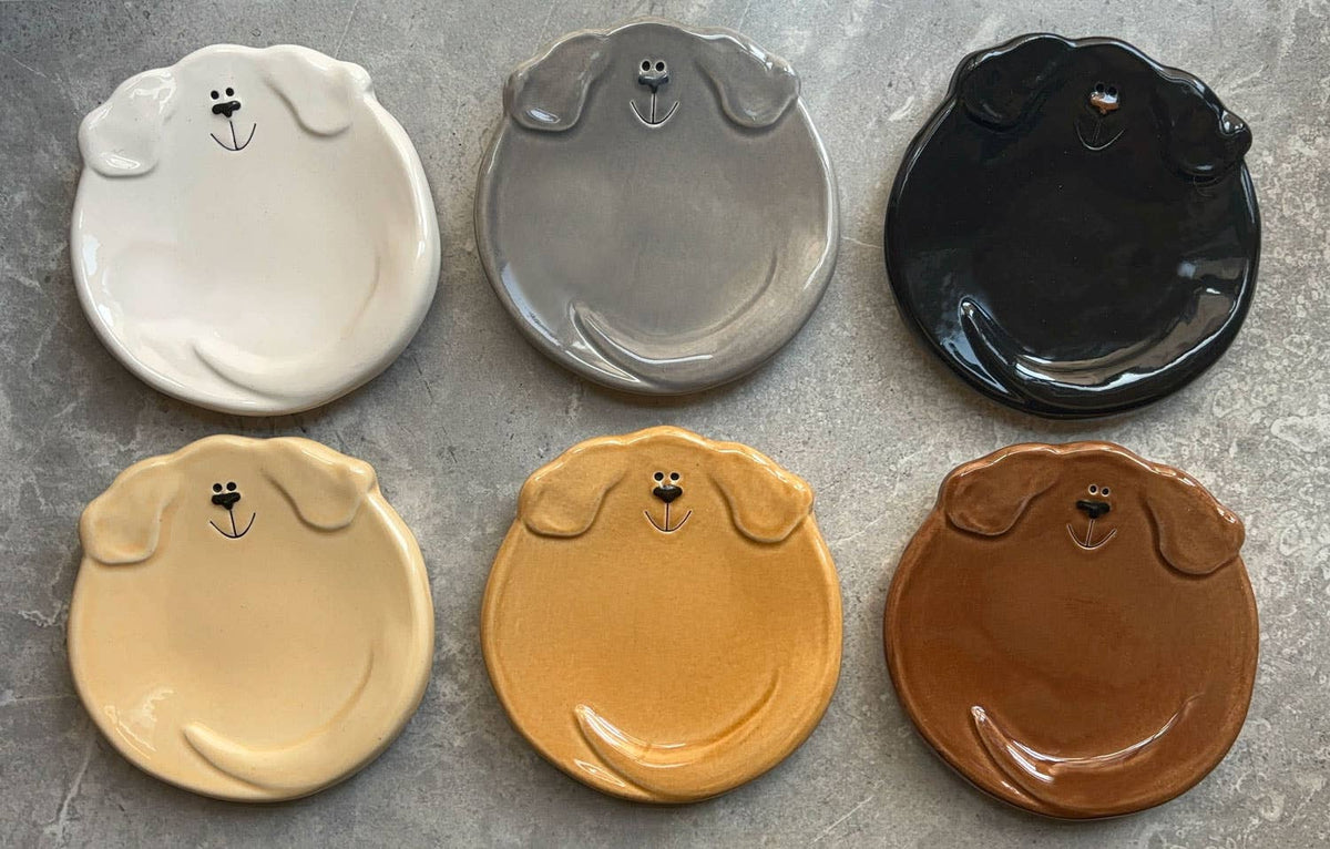 Set of six dog-shaped ceramic plates in different colors on a gray surface