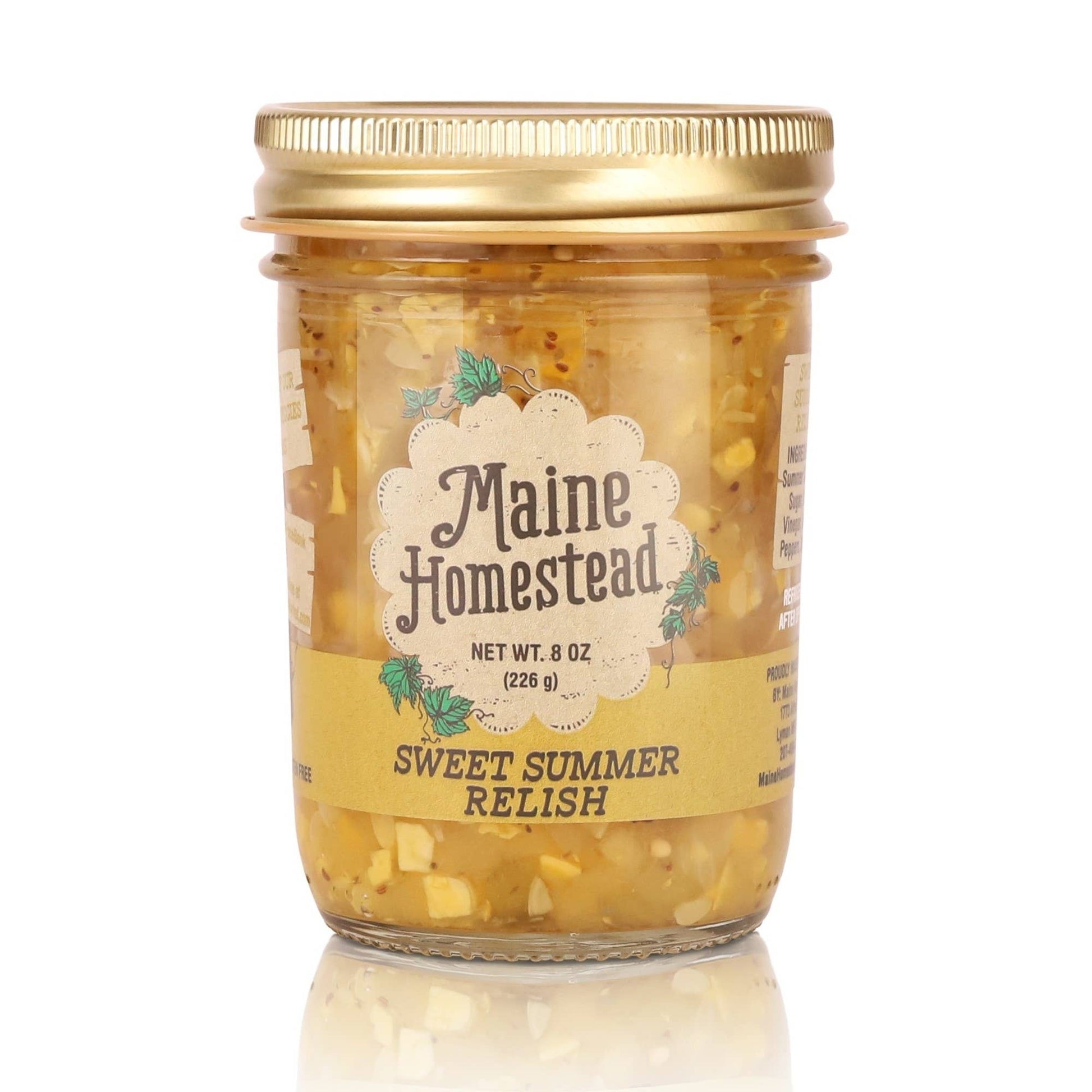 A glass jar of Maine Homestead Sweet Summer Relish with a gold metal lid and a cream-colored label, set against a plain white background with a soft reflection below.