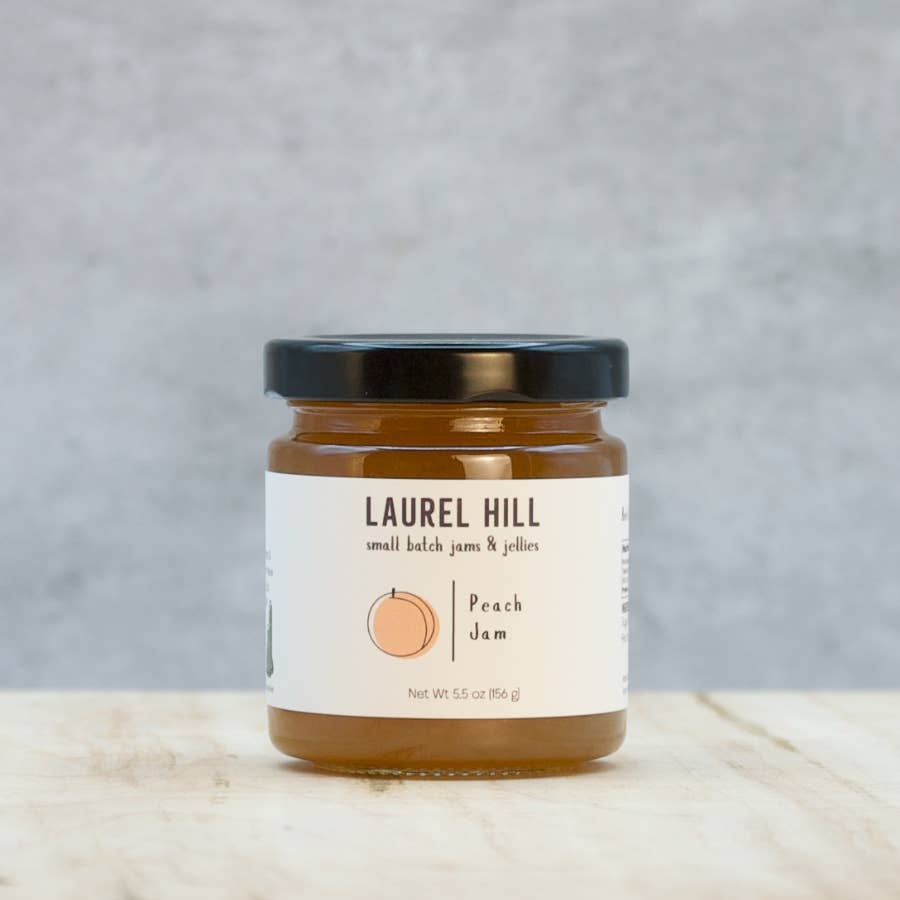 Jar of Laurel Hill peach jam on a wooden surface with a gray background