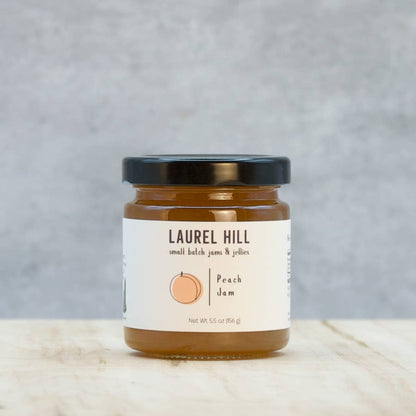Jar of Laurel Hill peach jam on a wooden surface with a gray background
