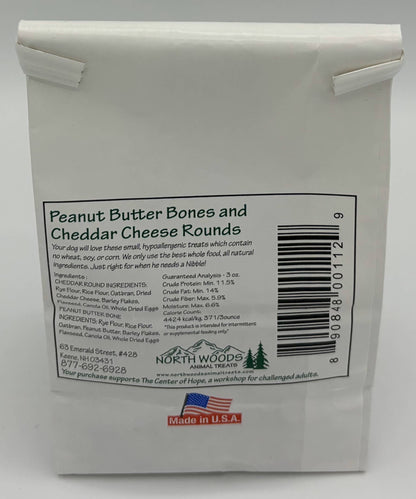 A white plastic bag of North Woods Peanut Butter Bones and Cheddar Cheese Rounds, showing the front label with product details, a barcode, and a small red 'Made in U.S.