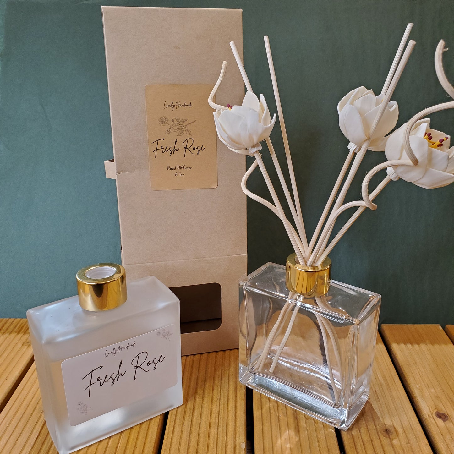 Clear diffuser bottle with white floral sticks on a green surface