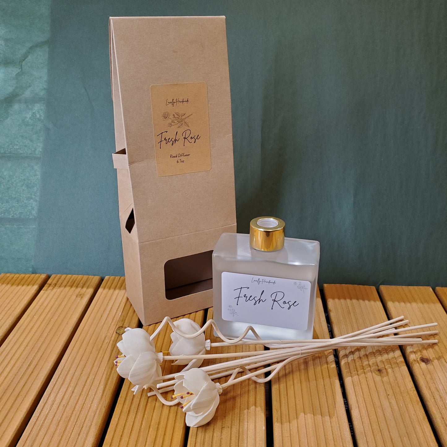 Diffuser bottle with 'Fresh Rose' label and reeds on a wooden surface