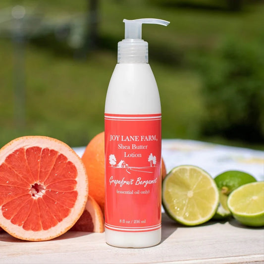 Joy Lane Farm Shea Butter Lotion bottle with citrus fruits on a wooden surface