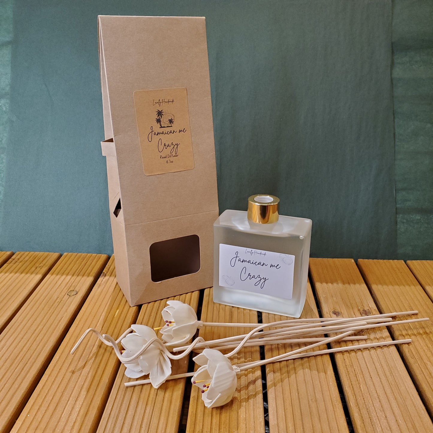 Diffuser bottle with floral reeds and packaging on a wooden surface