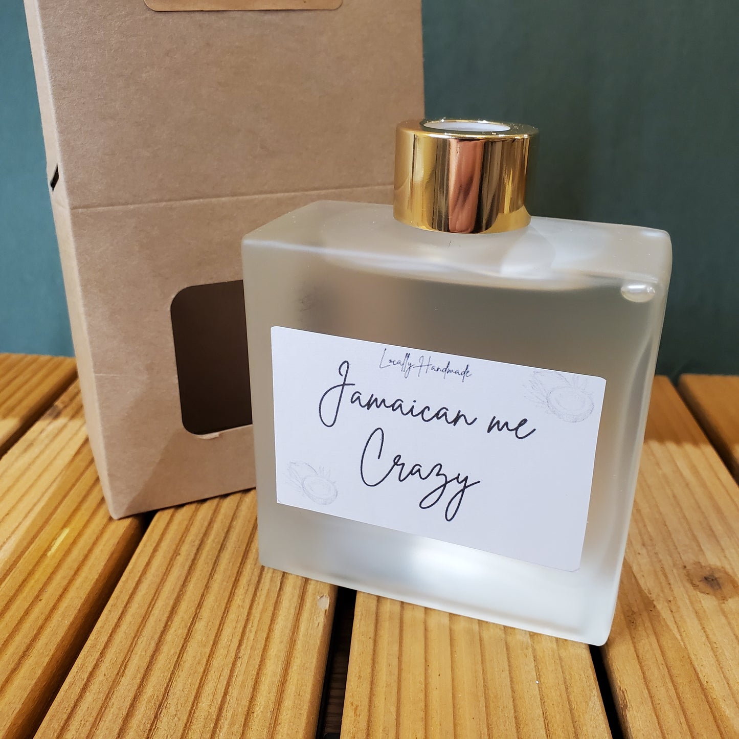 Perfume bottle with a gold cap and 'Jamaican me Crazy' label on a wooden surface.