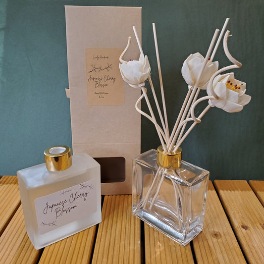 Perfume bottle with floral diffuser sticks on a wooden surface