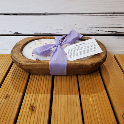 Wooden bowl with a candle and purple ribbon on a wooden surface