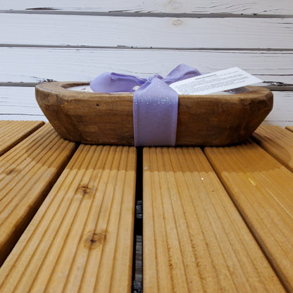 Wooden bowl with a purple ribbon on a wooden surface