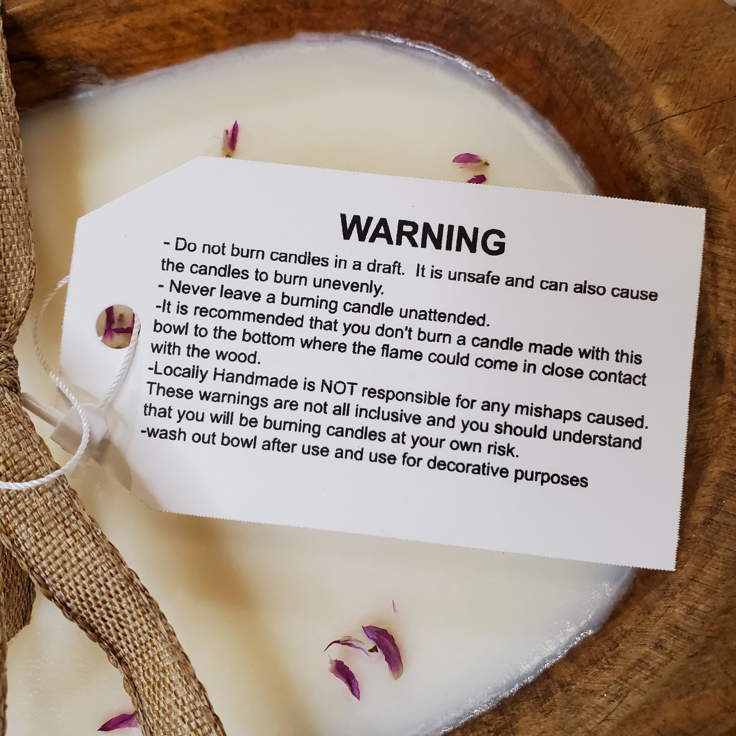 Candle with a warning label on a wooden surface