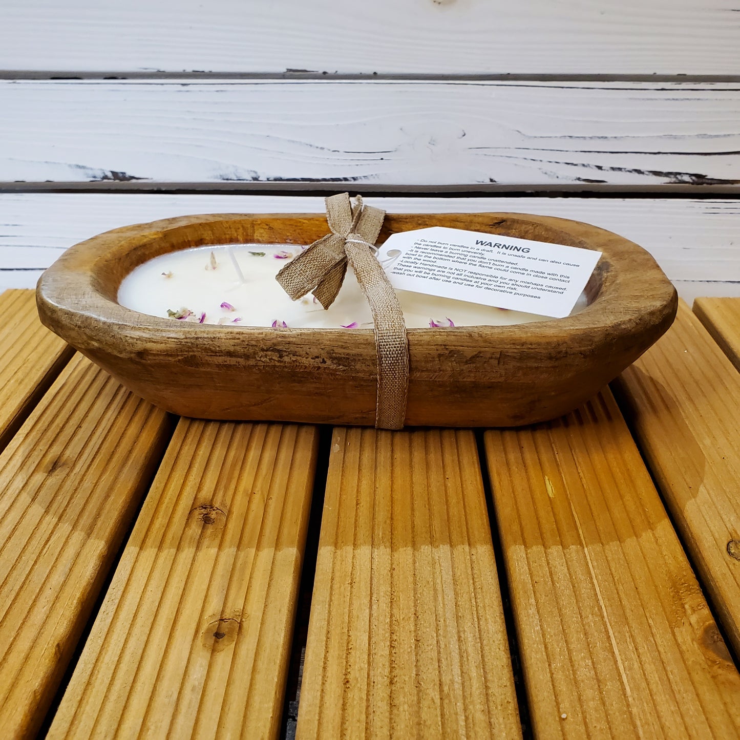 Wooden bowl with a candle and gift tag on a wooden surface