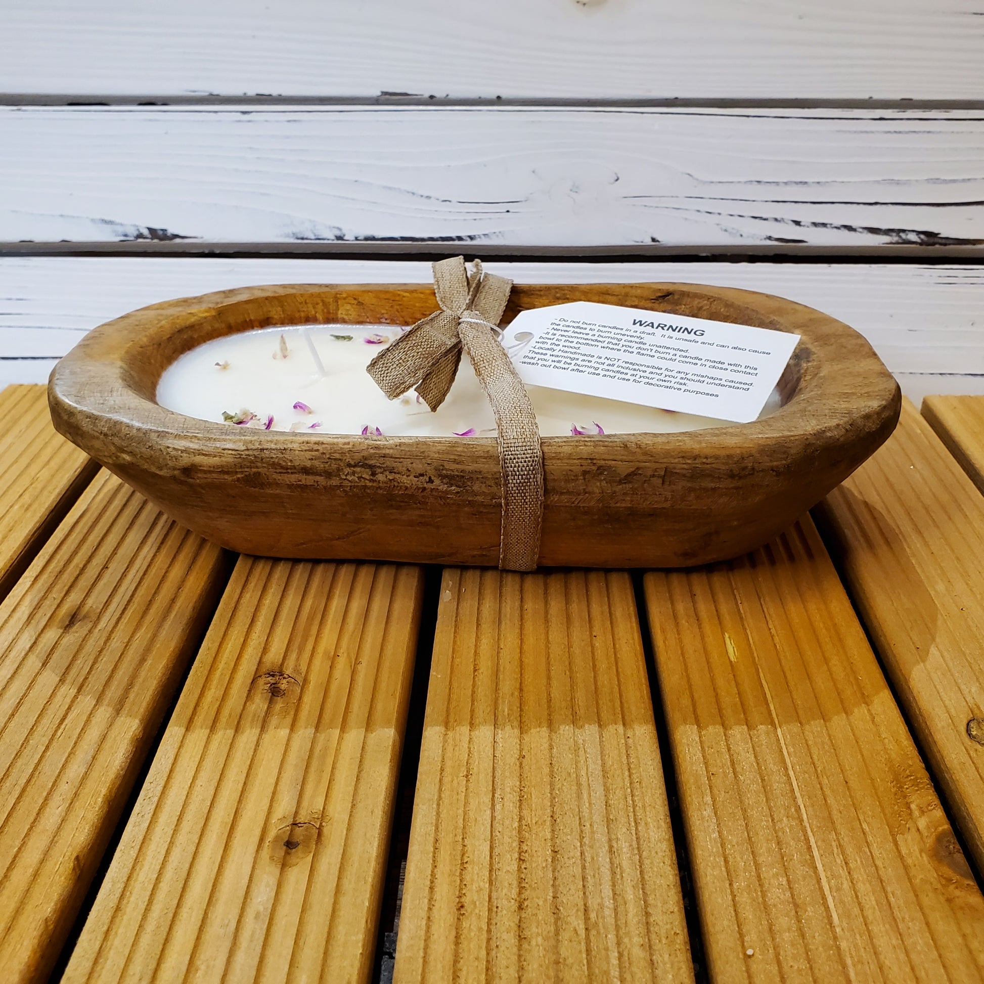 Wooden bowl with a candle and gift tag on a wooden surface
