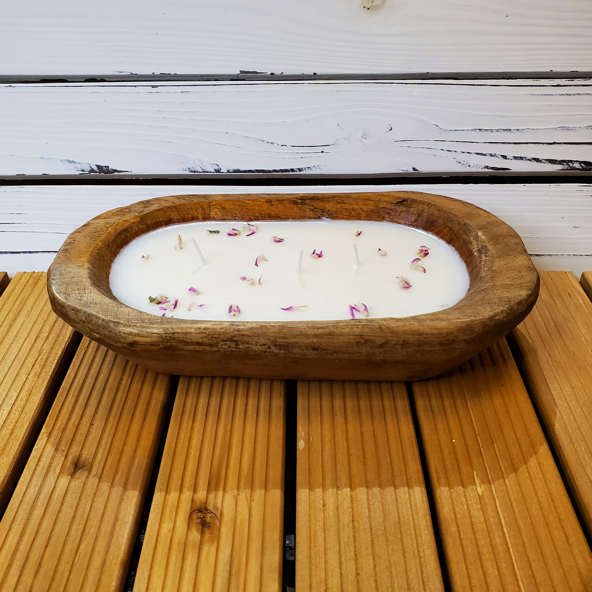 Wooden bowl with a candle inside on a wooden surface