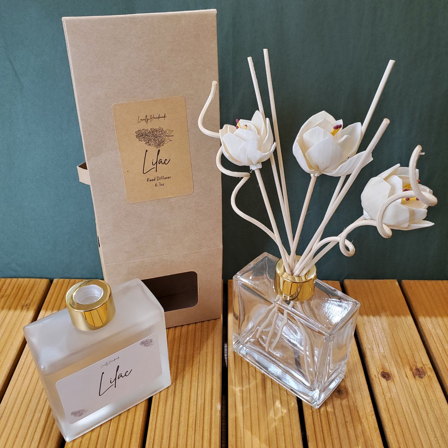 Decorative diffuser with white tulip-shaped nozzles and a clear bottle labeled 'Lychee' on a wooden surface.