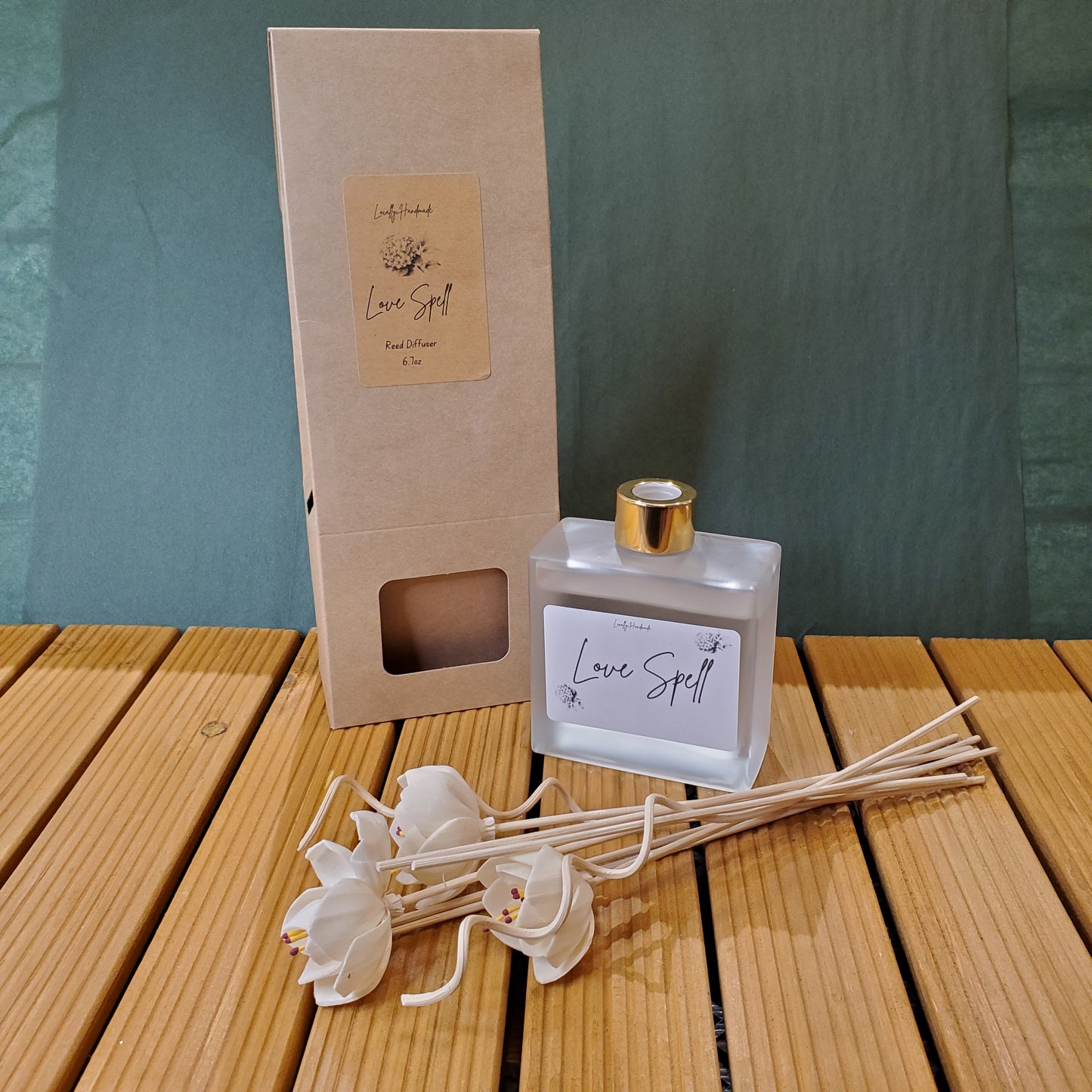 Diffuser bottle with packaging and decorative sticks on a wooden surface