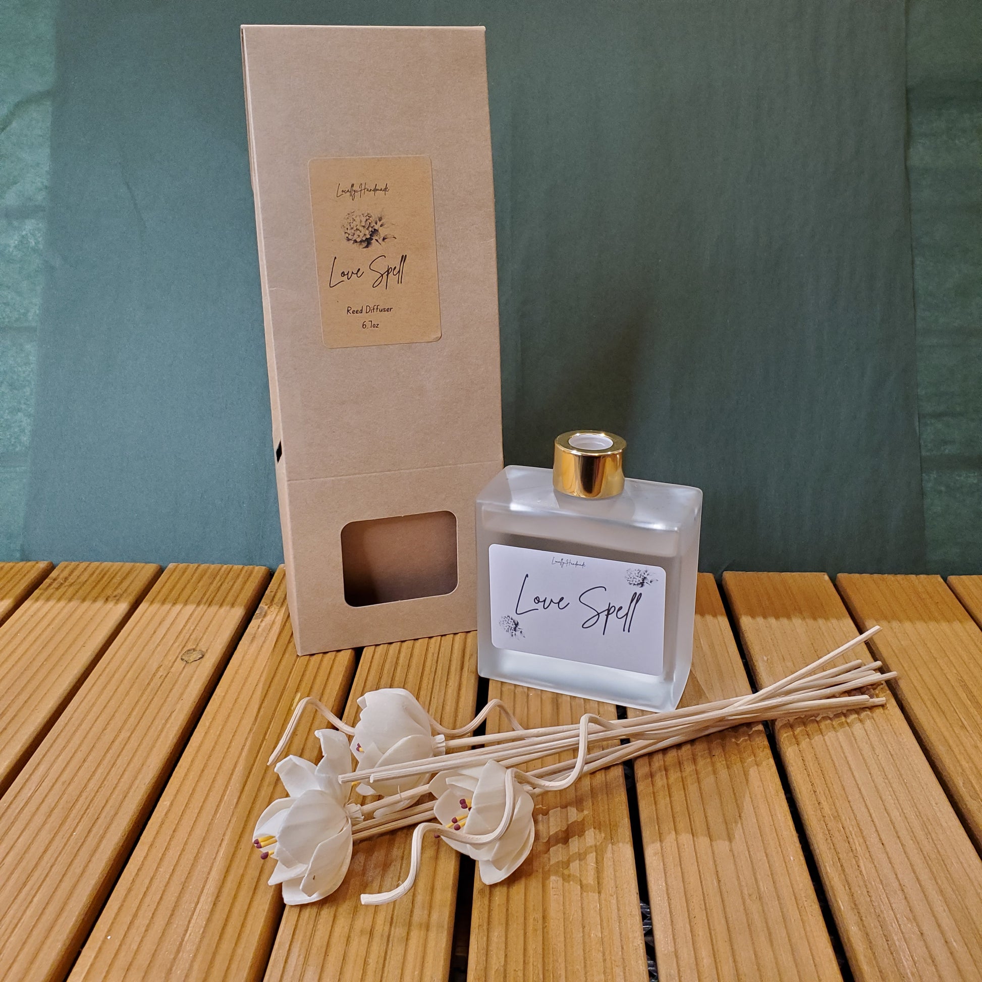 Diffuser bottle with packaging and decorative sticks on a wooden surface