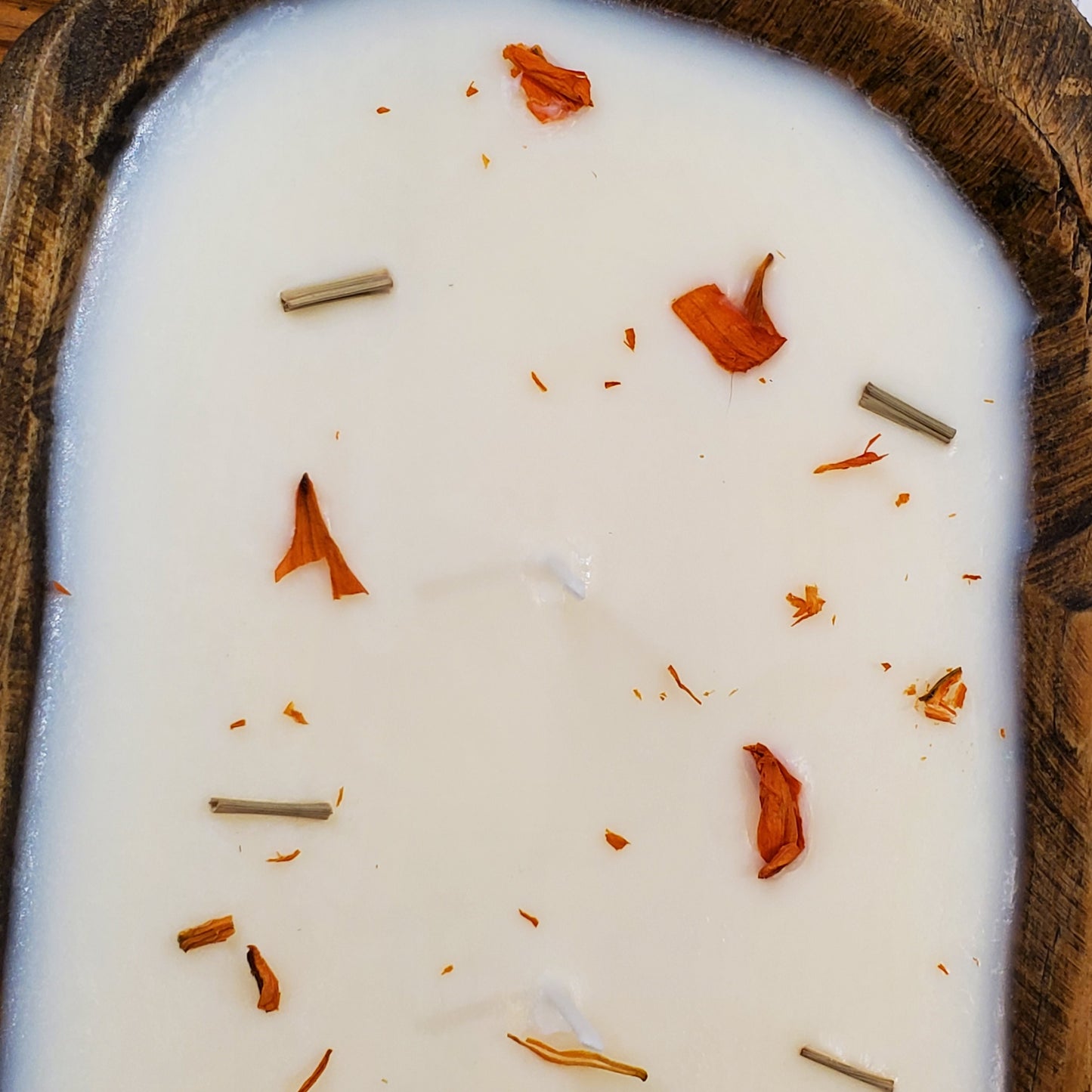 Candle in a wooden holder with dried leaves and sticks on top