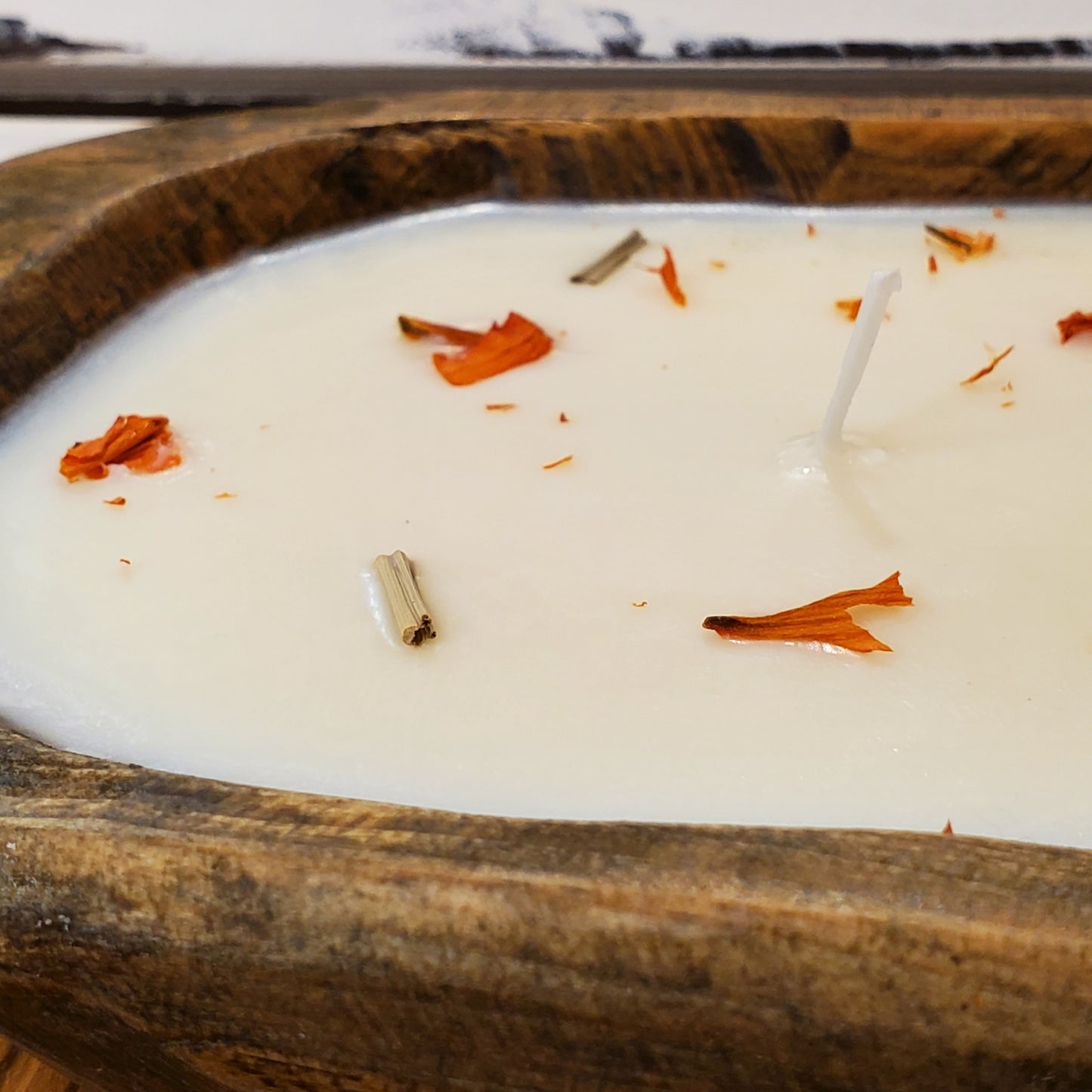 Candle with orange petals in a wooden holder