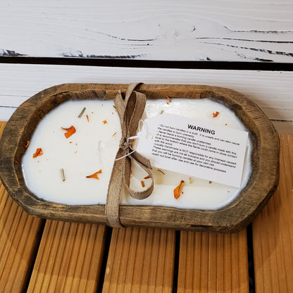 Candle in a wooden dish with a warning label on a wooden surface