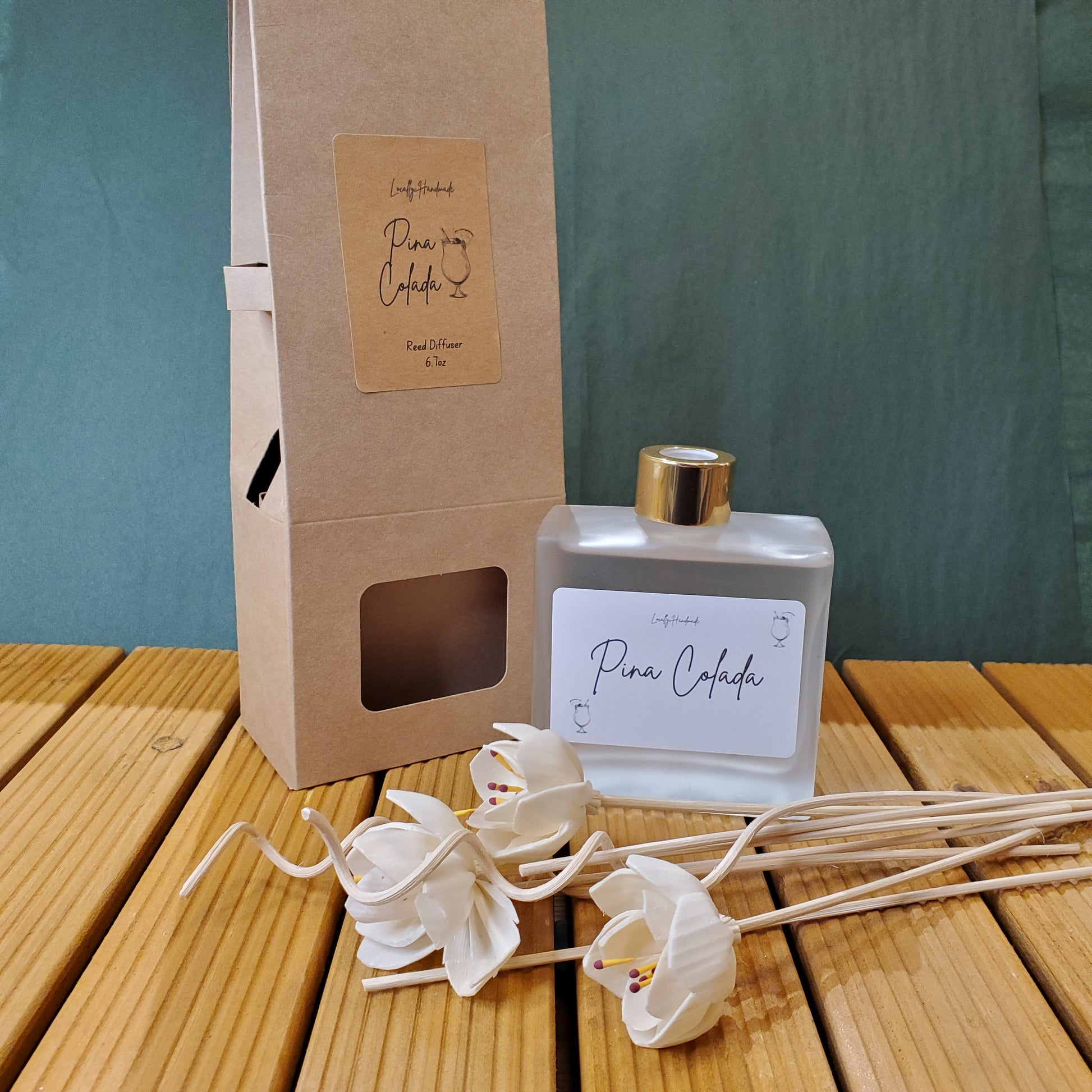 Perfume bottle with a gold cap and white label on a cardboard box, with flowers in the background.
