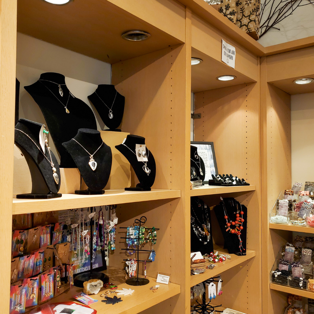 Jewelry store display with necklaces on mannequins and various items on shelves.